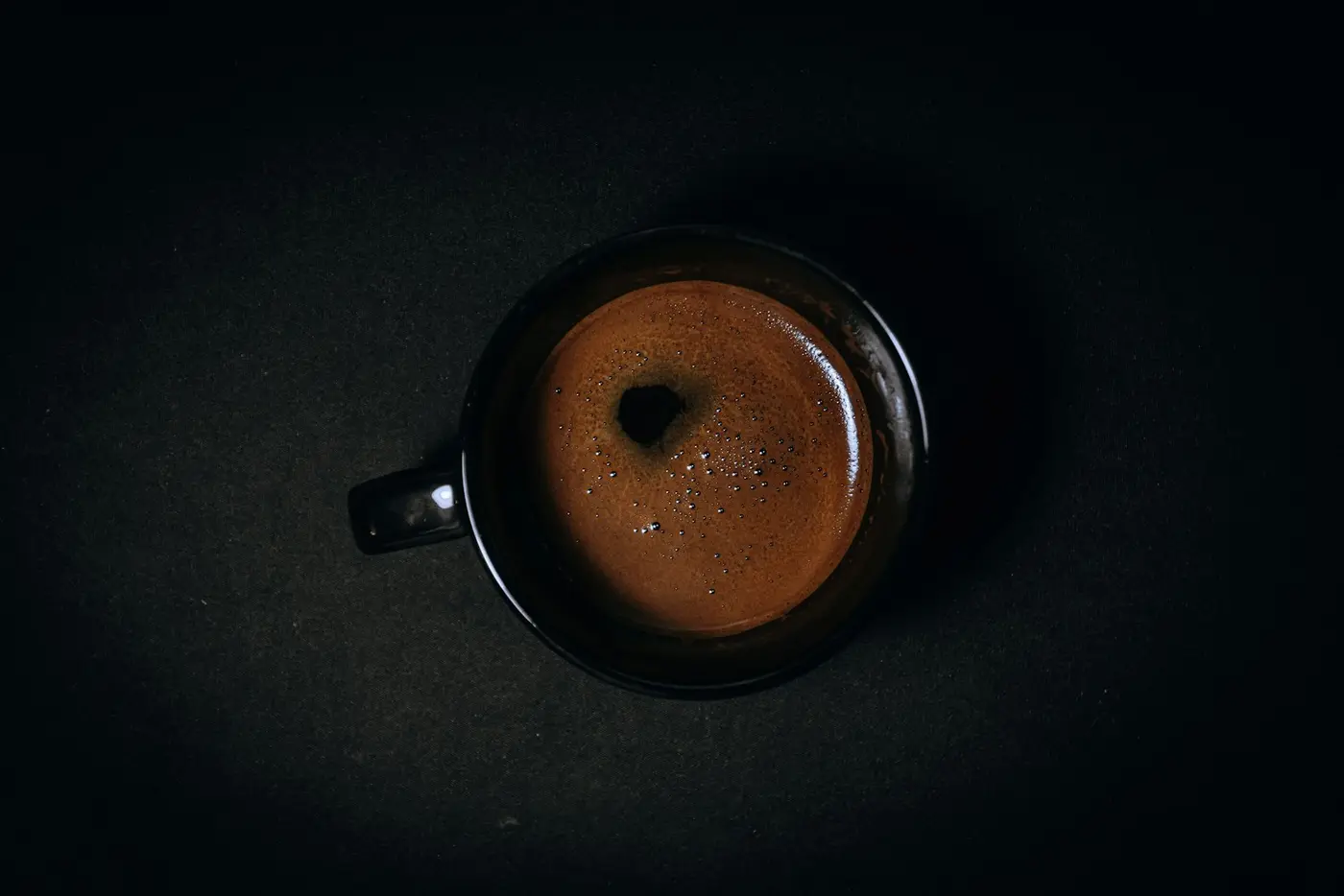 Secangkir kopi hitam di atas permukaan gelap