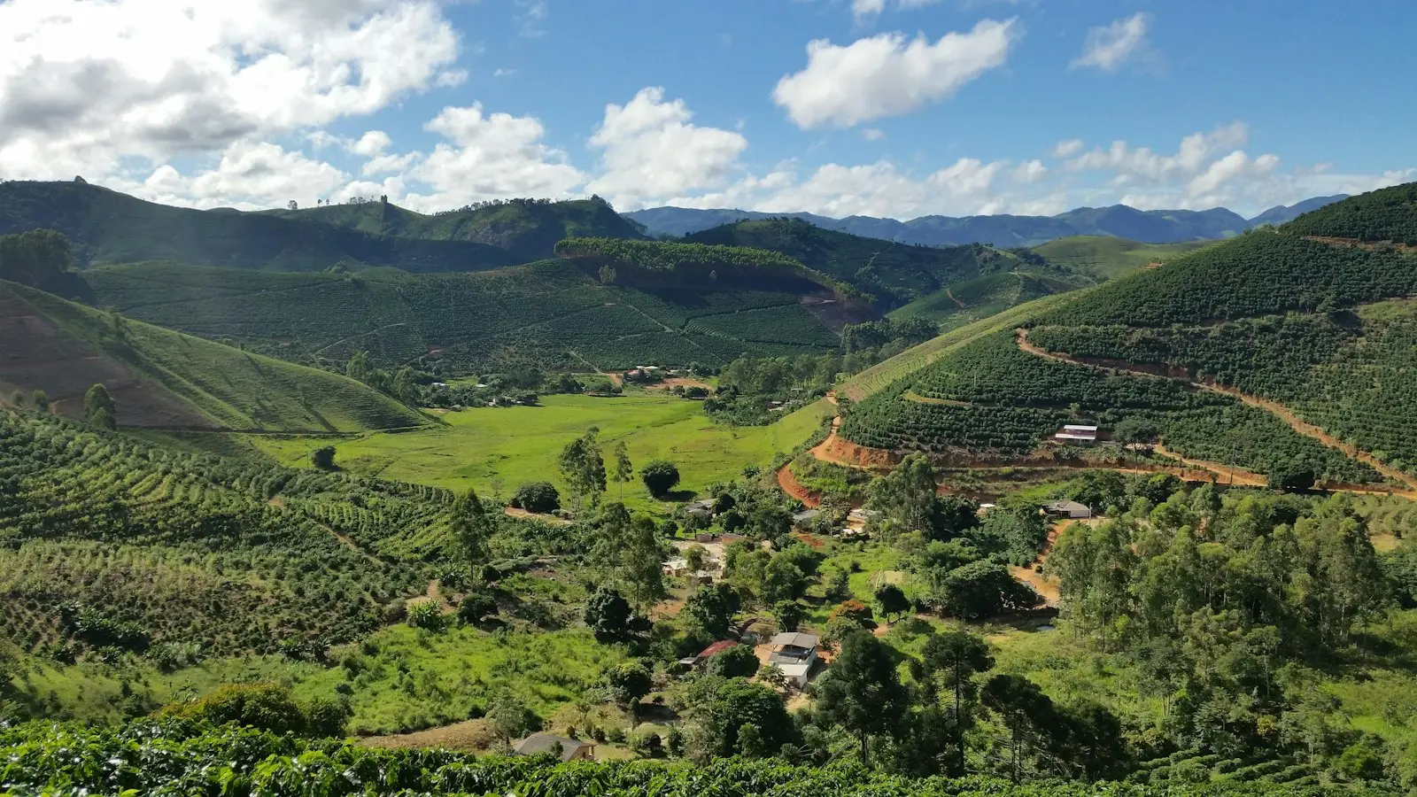 Lembah dataran tinggi yang hijau dengan kebun dan ladang di bawah pegunungan